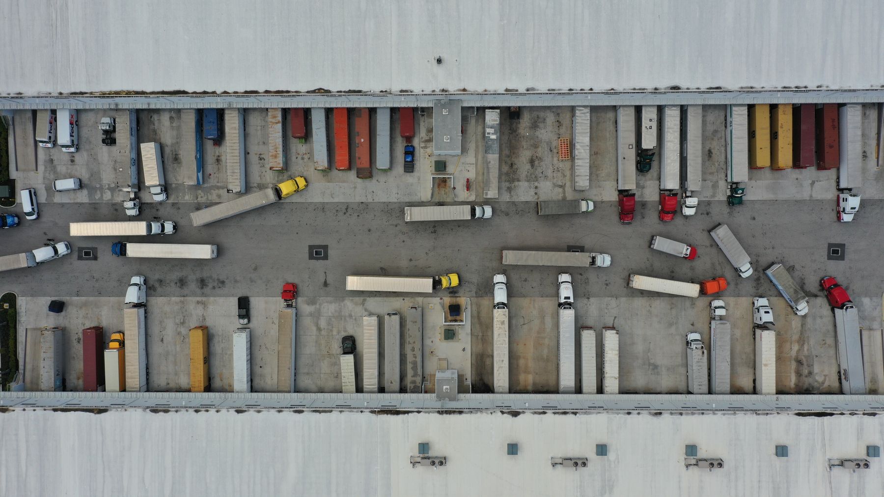 Aerial view of a busy truck court with tractors and trailers at dock doors